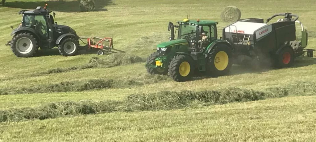 Traktor mit Ballenspresse am Feld - landwirtschaftliche Dienstleistung